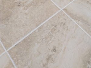 Beige ceramic tile floor with clean grout lines, demonstrating the effect of grout sealing to maintain appearance and prevent staining.
